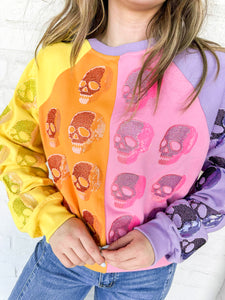 Queen of Sparkles Colorblock Multi Skull Sweatshirt with color blocking stripes of yellow, orange, pink and light purple with sequin beaded skulls