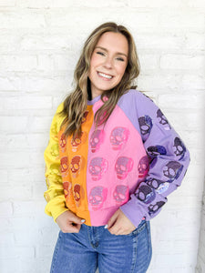 Queen of Sparkles Colorblock Multi Skull Sweatshirt with color blocking stripes of yellow, orange, pink and light purple with sequin beaded skulls