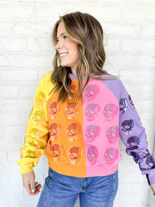 Queen of Sparkles Colorblock Multi Skull Sweatshirt with color blocking stripes of yellow, orange, pink and light purple with sequin beaded skulls