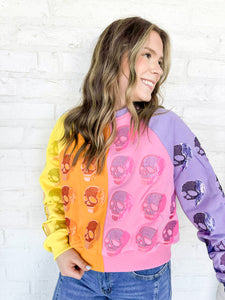 Queen of Sparkles Colorblock Multi Skull Sweatshirt with color blocking stripes of yellow, orange, pink and light purple with sequin beaded skulls