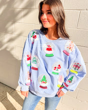 Load image into Gallery viewer, Queen of Sparkles light blue Snow Globe sequin sweatshirt with holiday snow-globe motifs, modeled with jeans outdoors