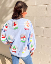 Load image into Gallery viewer, Queen of Sparkles light blue Snow Globe sequin sweatshirt with holiday snow-globe motifs, modeled with jeans outdoors